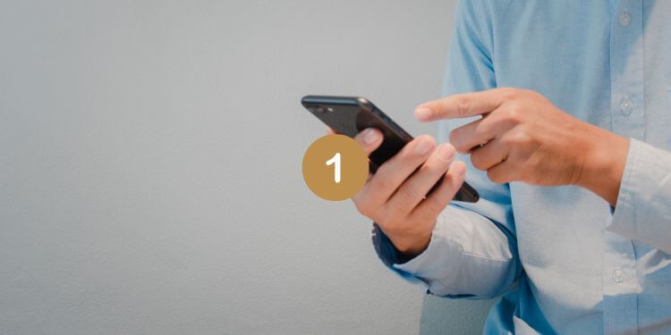 Person in a blue shirt using a smartphone for texting.