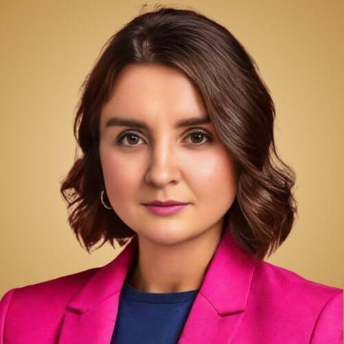 Portrait of a woman wearing a pink blazer against a brown background, with a confident expression.