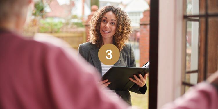 Smiling woman with a clipboard at the door, engaging in conversation on a sunny day.