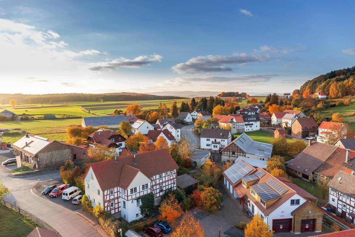 Aerial view of a modern countryside village with solar-roof homes during autumn — ideal example of property market trends shifting post-COVID for homeowners wanting to sell home quick